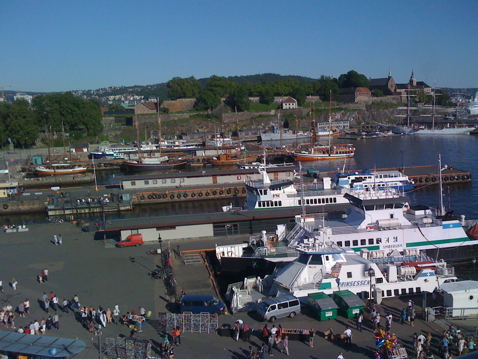 Passenger ferries and sailing ships at Oslo harbour below Akershus Fortress